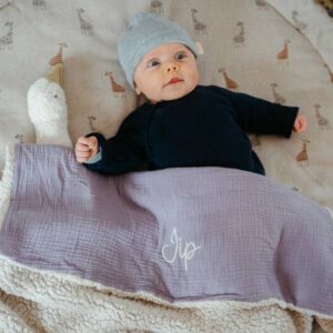 Baby onder een gepersonaliseerde lila teddy wiegdeken