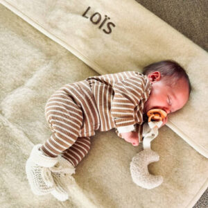 Baby onder een Flat White ledikantdeken van merinowol