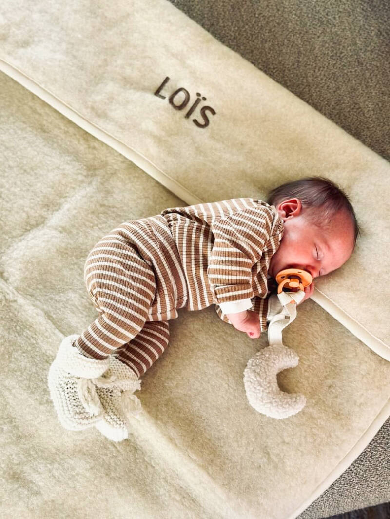 Baby onder een Flat White ledikantdeken van merinowol