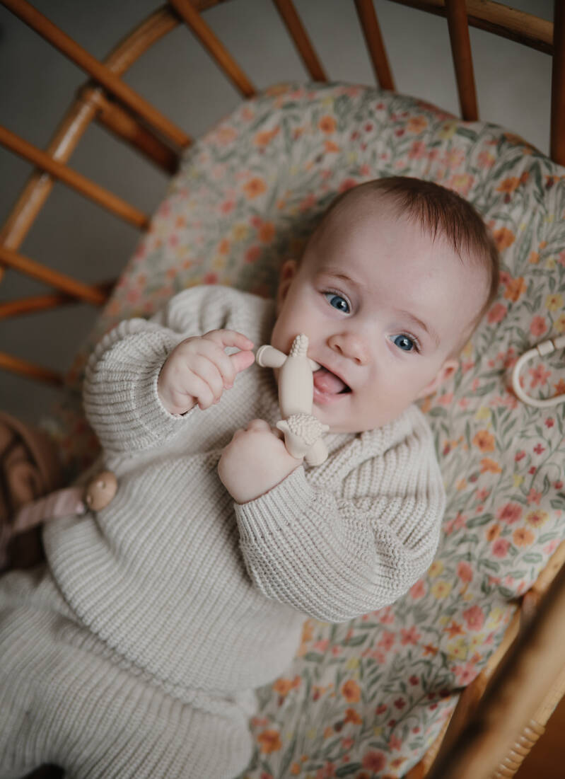 Baby speelt met een crèmekleurige lammetje-bijtfiguur